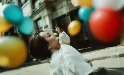 a woman on a street with balloons flying around her
