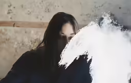 a woman with long dark hair looking down at her phone