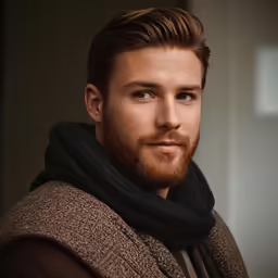 a male in a sweater and scarf posing for a photo