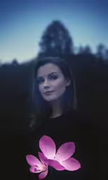 woman in a black sweater with a purple flower