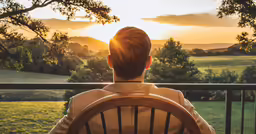 back view of a person sitting on a chair with the sun setting behind them