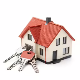 a house with a key attached to it and three keys that have been placed in front of the house