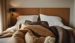 a bed in a hotel room with pillows and blanket