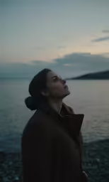 woman standing on beach looking up at the sky