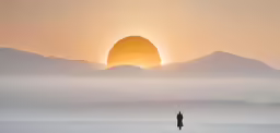 silhouette of man standing in snowy landscape against a hazy sky