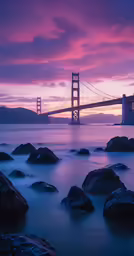 a sunset over a body of water with a bridge in the distance