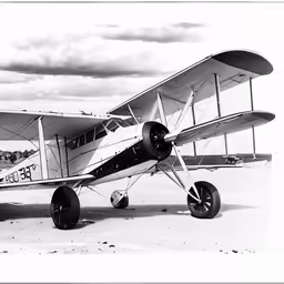 the small airplane is parked on a sandy field