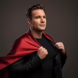 a man wearing a red cape standing in front of a black backdrop