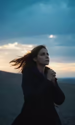 the woman stands alone as the sun sets