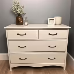 a white dresser is holding a vase with flowers on top