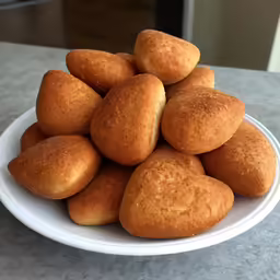 a white plate topped with fried and uncooked doughnuts