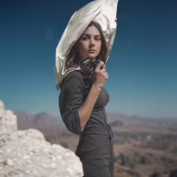 a woman is standing on a mountain posing with her camera