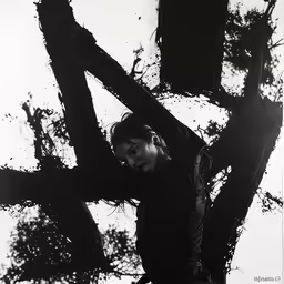 a lady is standing behind a tree in the rain