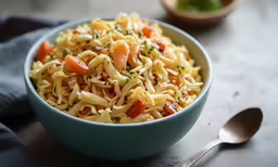 a blue bowl filled with pasta sitting next to a spoon