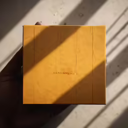 a hand holding an opened yellow paper notebook
