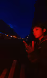 a boy sitting on a bench pointing a finger