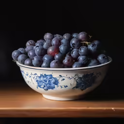 there are grapes in the blue and white bowl