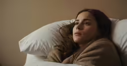 a young girl is laying on her bed alone