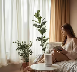 a woman sitting on a bed holding a book