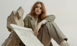 woman in white sneakers leaning on a piece of wood