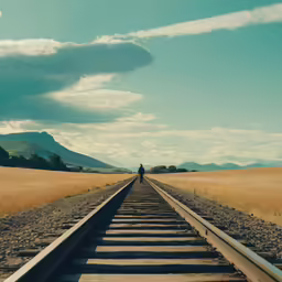 a person walking along train tracks on a cloudy day