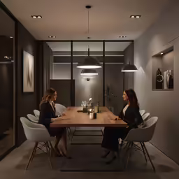 two women are sitting at a table and talking