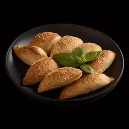 some croissants and leaves sit on a black plate