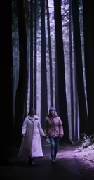 two young women holding hands and walking in the woods