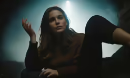 a woman sitting on a rock in the dark