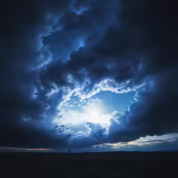 a view of the sun and dark clouds from a field