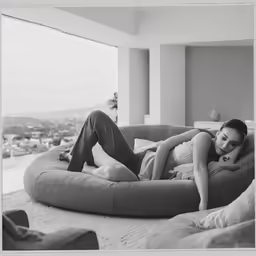 an old photo of a woman lying down on a bean bag chair