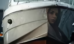 woman sits on the back of a boat and looks off into the distance