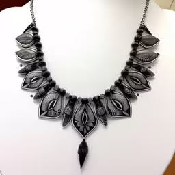 an intricate necklace with black beads and leaves,a necklace is shown sitting on a mannequin