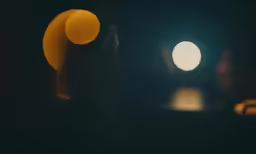 a woman standing in front of a light in the dark