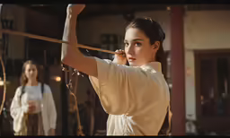 two women wearing white clothes holding up some kind of string