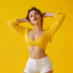a model poses in a yellow cropped top and white shorts
