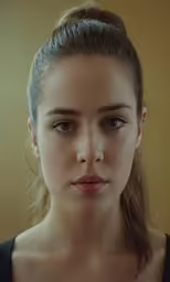 a woman with her hair styled into a bun looking directly in camera