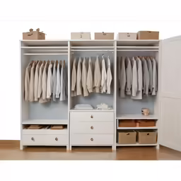 a small white dresser has some clothes hanging on it
