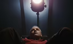 a man sitting in a recliner looking up with an odd light above him