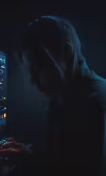 a woman typing on a keyboard inside of a darkened room