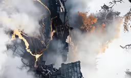 the building in the foreground is on fire with many flames