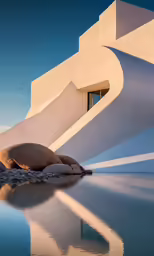 an image of water near a building that has rocks in front of it