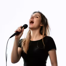 a woman singing into a microphone while standing
