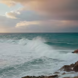 a man stands at the edge of a rocky cliff, while the ocean breaks up