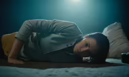 a woman lays on her side on the floor with light streaming through her