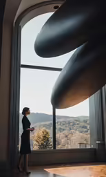 a woman in black dress standing in front of a large sculpture