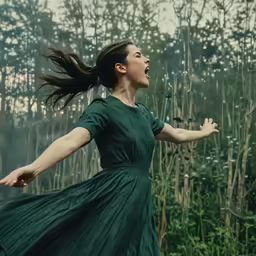 a woman in a long green dress and her hair flying around