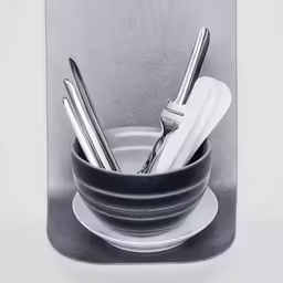 three knives and two forks in a black and white bowl