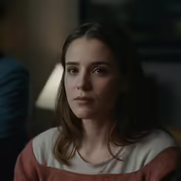 woman in a red sweater stares into the camera