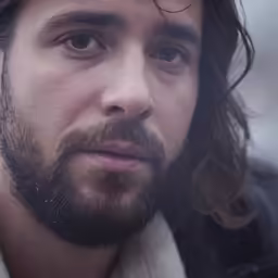 a man with long hair wearing a black jacket
